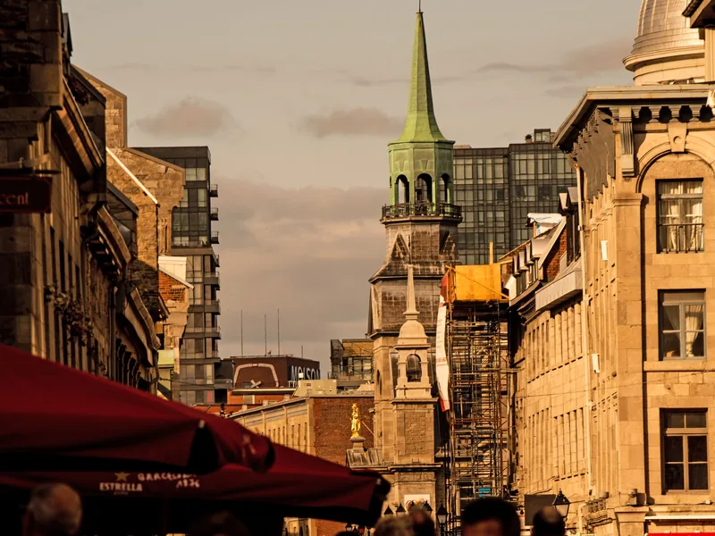 A busy street in Old Montreal with historic stone buildings and a church spire