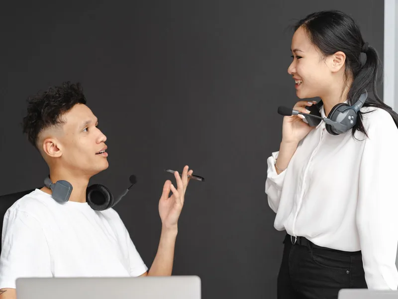 Two colleagues wearing headsets, talking with each other